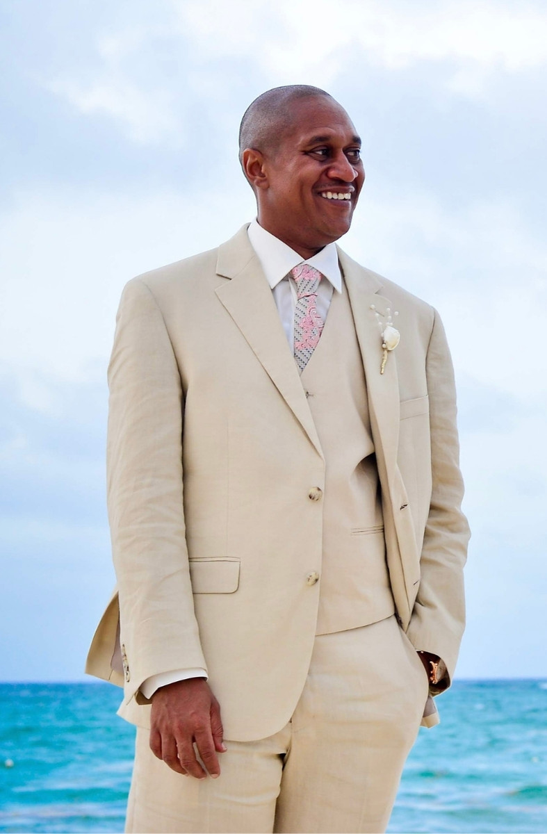 Vaughn Parker Jr. smiling by the ocean in a cream suit
